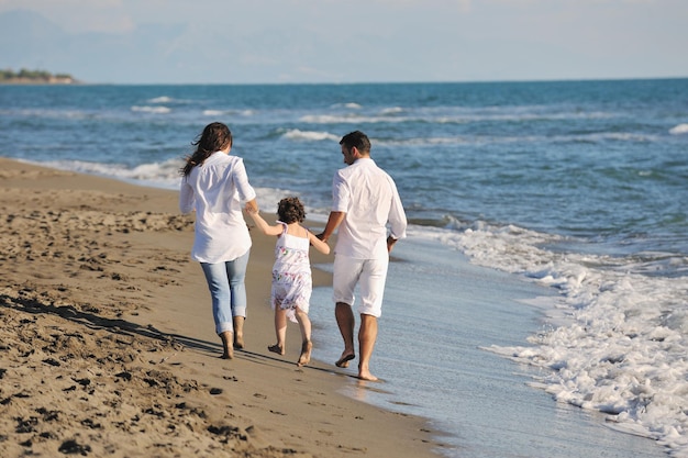 família jovem feliz em roupas brancas se diverte nas férias na bela praia