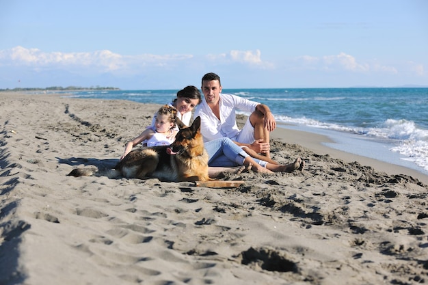 família jovem feliz em roupas brancas se divertir e brincar com lindo cachorro de férias na bela praia