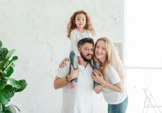 Família jovem feliz. Homem, mulher e filha. Fundo claro, tiro de estúdio. Casamento inter-racial, diferentes nacionalidades