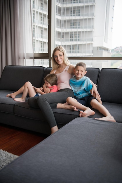 Família jovem feliz jogando junto com o tablet em casa sentado no sofá