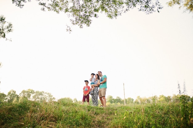 Família jovem feliz: mãe, pai, filho de dois filhos na natureza se divertindo.