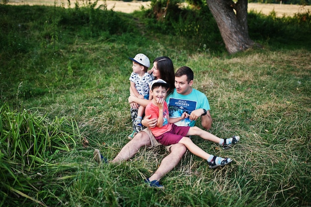 Família jovem feliz: mãe, pai, filho de dois filhos na natureza se divertindo.