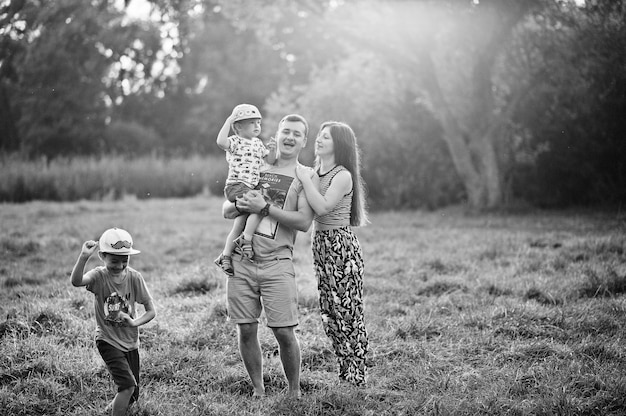 Família jovem feliz: mãe, pai, filho de dois filhos na natureza se divertindo.