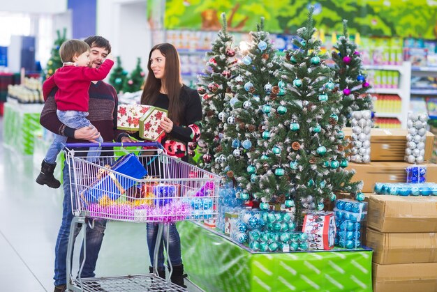 Família jovem feliz no supermercado escolhe presentes para o natal