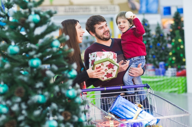 Família jovem feliz no supermercado escolhe presentes para o natal