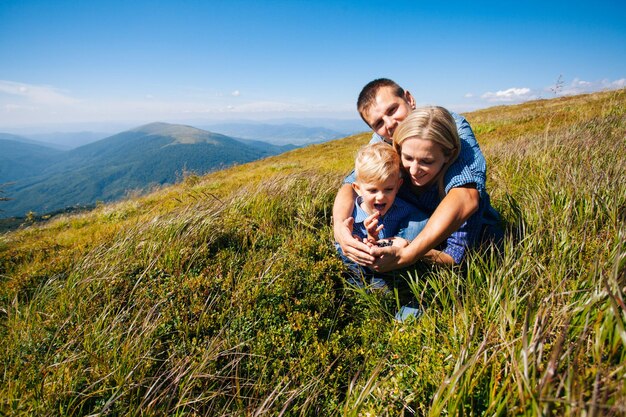 Família jovem feliz reúne bagas nas montanhas