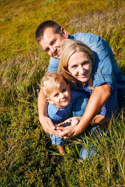 Família jovem feliz reúne bagas nas montanhas