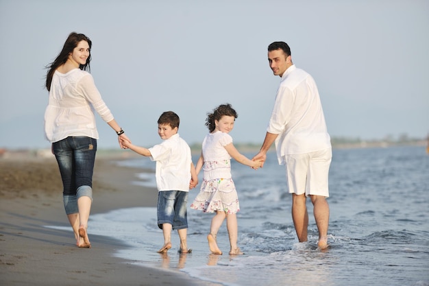 família jovem feliz se diverte na praia correr e pular ao pôr do sol