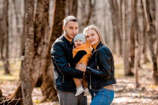 Família jovem passeio no parque na primavera com uma criança em um carrinho. pais felizes