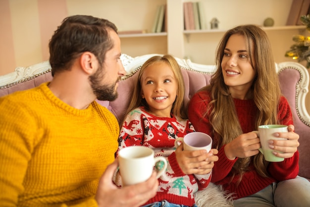 Família jovem sentada no sofá e se sentindo confortável