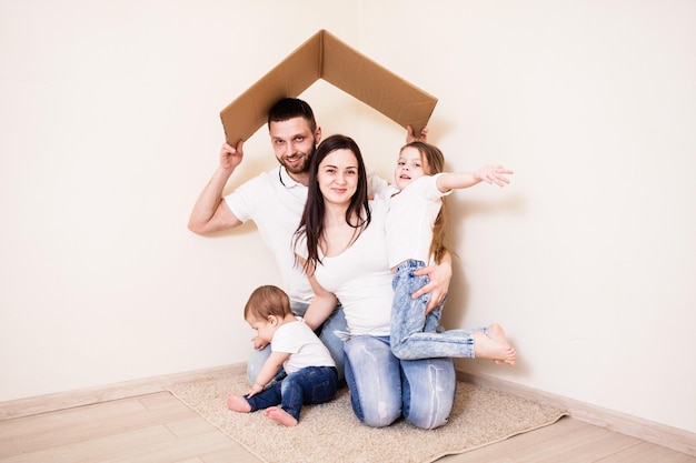 Família jovem sob o abrigo de papel. Pai cuidando de sua família, conceito