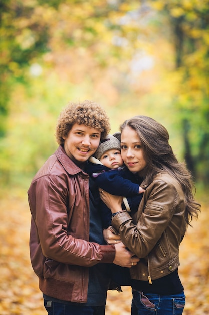 Familia joven, abrazar, en, otoño, en el estacionamiento