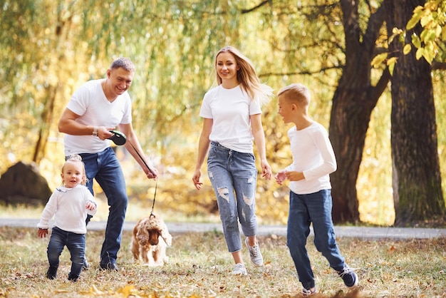 Familia joven alegre dar un paseo juntos en un parque de otoño.