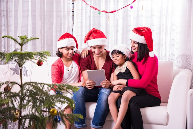 Familia joven asiática india celebrando la Navidad con regalo mientras usa gorro de Papá Noel