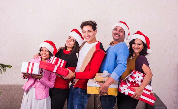 Familia joven asiática india celebrando la Navidad con regalo mientras usa gorro de Papá Noel