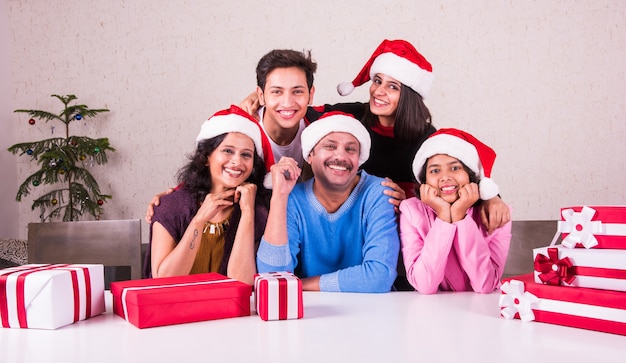 Familia joven asiática india celebrando la Navidad con regalo mientras usa gorro de Papá Noel