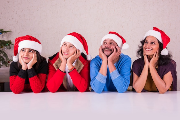 Familia joven asiática india celebrando la Navidad con regalo mientras usa gorro de Papá Noel