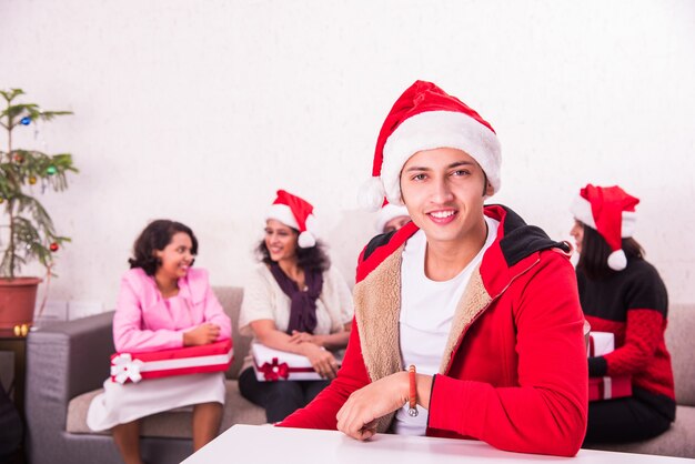 Familia joven asiática india celebrando la Navidad con regalo mientras usa gorro de Papá Noel