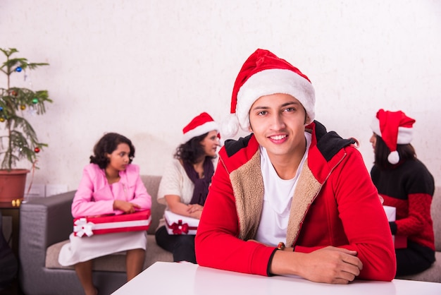 Familia joven asiática india celebrando la Navidad con regalo mientras usa gorro de Papá Noel