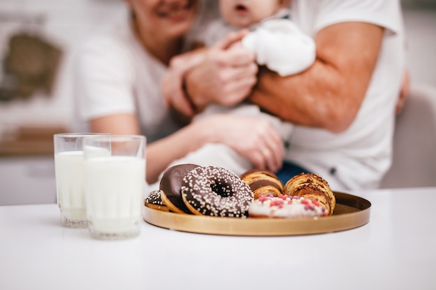 Una familia joven con un bebé en brazos tomará leche y desayunará