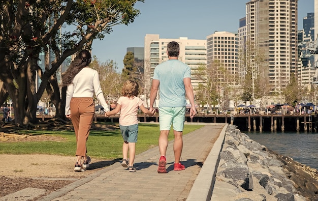 Familia joven caminando en el parque con hijo vista trasera padres