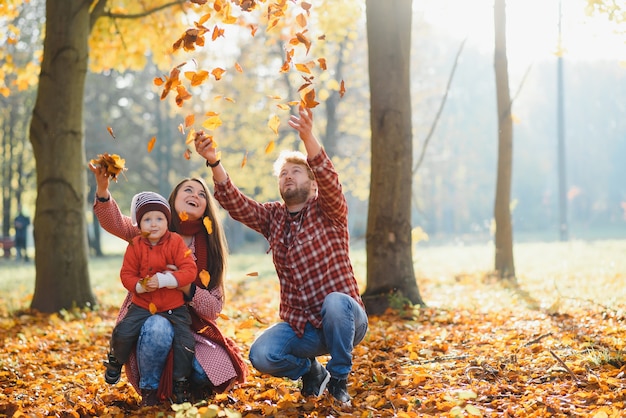 Familia joven caminando en el parque. Otoño.