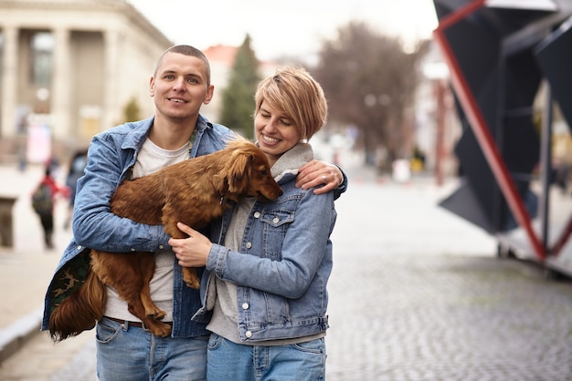 Familia joven caminando con un perro por las calles de la ciudad.