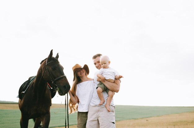 Una familia joven se divierte en el campo. Padres e hijos con un caballo