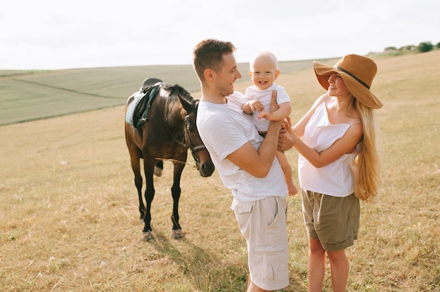 Una familia joven se divierte en el campo. Padres e hijos con un caballo