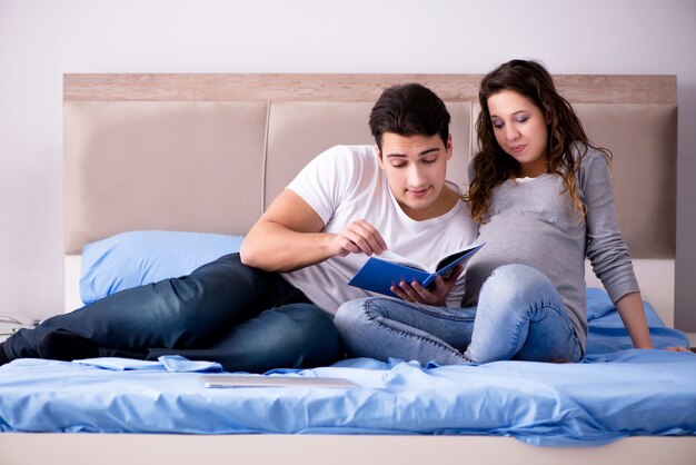 Familia joven con esposa embarazada esperando bebé en la cama