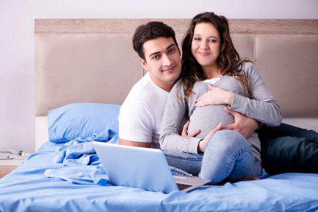 Familia joven con esposa embarazada esperando bebé en la cama