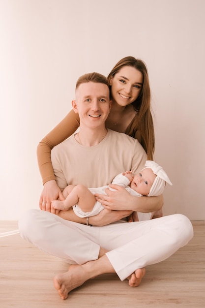 Familia joven con estilo fotografiada con un pequeño y hermoso bebé La familia expresa amor y asombro el uno al otro Concepto de familia y crianza