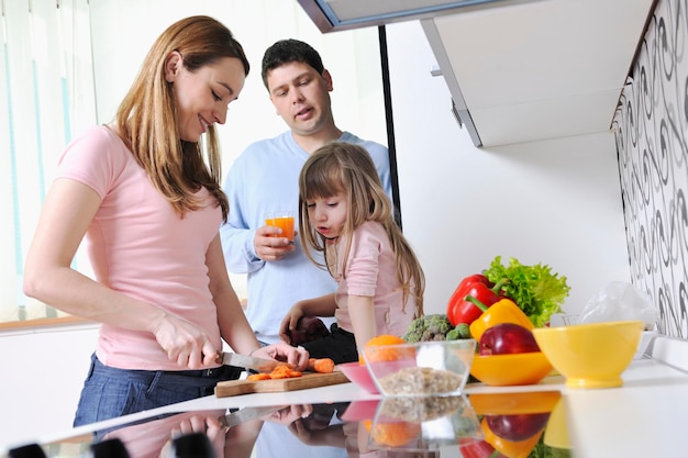 familia joven feliz almuerza con frutas frescas y comida vegetal en una cocina luminosa