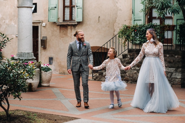 Una familia joven feliz camina por el casco antiguo de Sirmione en Italia. Familia elegante en Italia en un paseo.