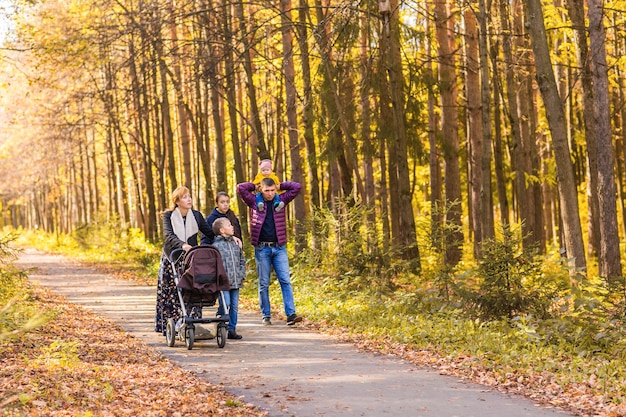 Familia joven feliz caminando por la calle al aire libre en la naturaleza de otoño