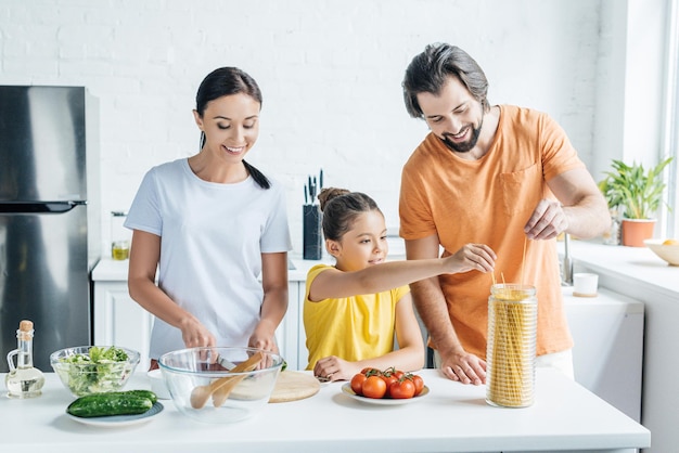 familia joven feliz cocinando una cena saludable juntos en la cocina