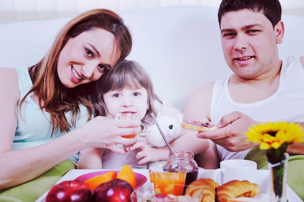 familia joven feliz desayunar en la cama por la mañana