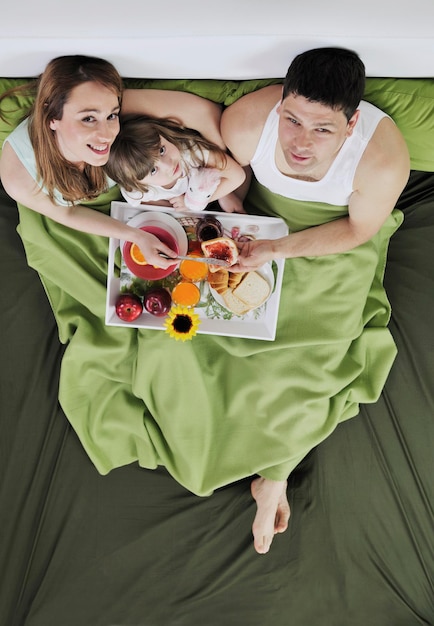 familia joven feliz desayunar en la cama por la mañana