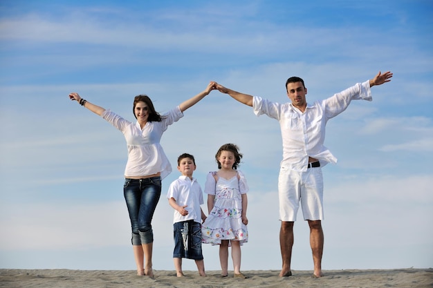 la familia joven feliz se divierte en la playa y muestra el cartel de casa con las manos conectadas mientras protege a los niños