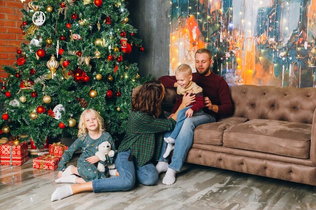 Familia joven feliz con dos hijos en el árbol de Navidad