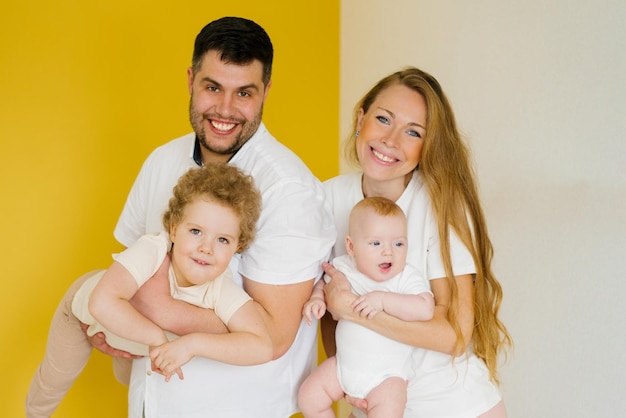 La familia joven feliz con dos niños pequeños en sus brazos se regocija