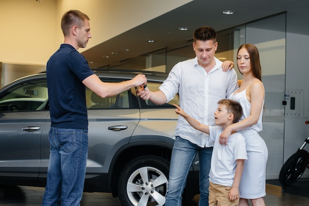 Una familia joven y feliz elige y compra un automóvil nuevo en un concesionario de automóviles. Comprar un auto nuevo.