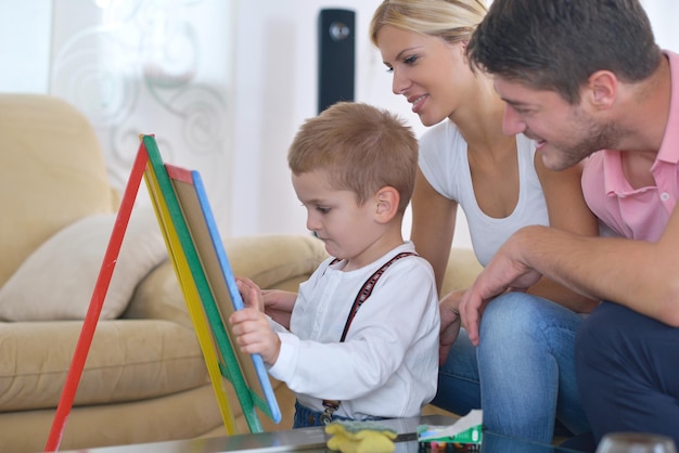familia joven feliz enseña lecciones y prepara a su hijo para la escuela mientras dibuja a bordo en casa