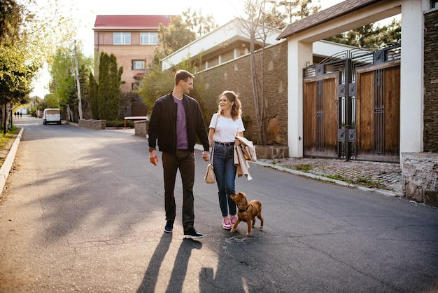 Familia joven feliz un hombre y una mujer enamorados se divierten caminando con su mascota perro en un parque de otoño en la naturaleza en otoño al aire libre, enfoque selectivo
