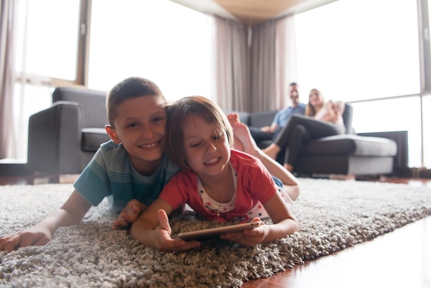 Familia joven feliz jugando juntos en casa. Niños usando tableta en el piso