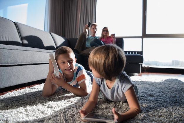 Familia joven feliz jugando juntos en casa. Niños usando tableta en el piso