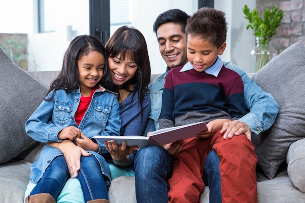 Familia joven feliz leyendo un libro juntos