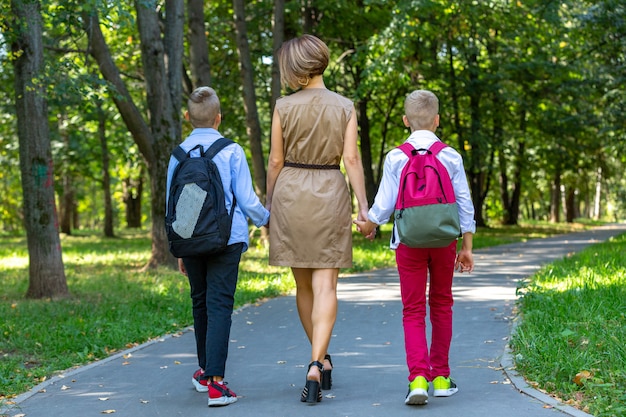 Familia joven feliz, madre con dos niños caminando en el parque. Concepto de estilo de vida saludable