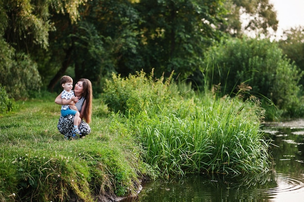 Familia joven feliz: madre con hijo de niños en la naturaleza divirtiéndose.