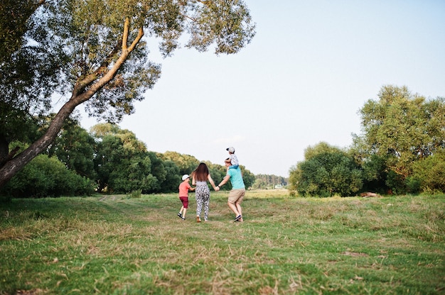 Foto familia joven feliz: madre, padre, hijo de dos hijos en la naturaleza divirtiéndose.